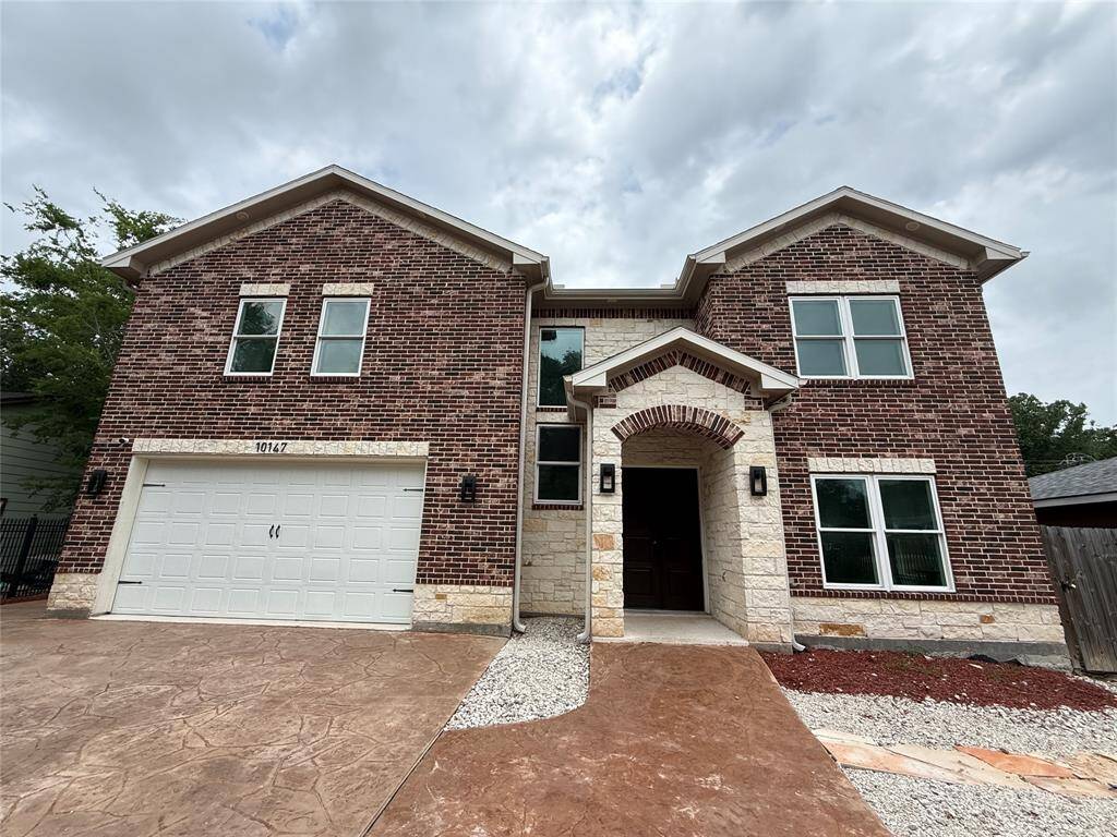 This is a modern two-story brick home with a two-car garage and a welcoming entrance featuring stone accents. The exterior has a clean and elegant look with multiple windows for natural light.