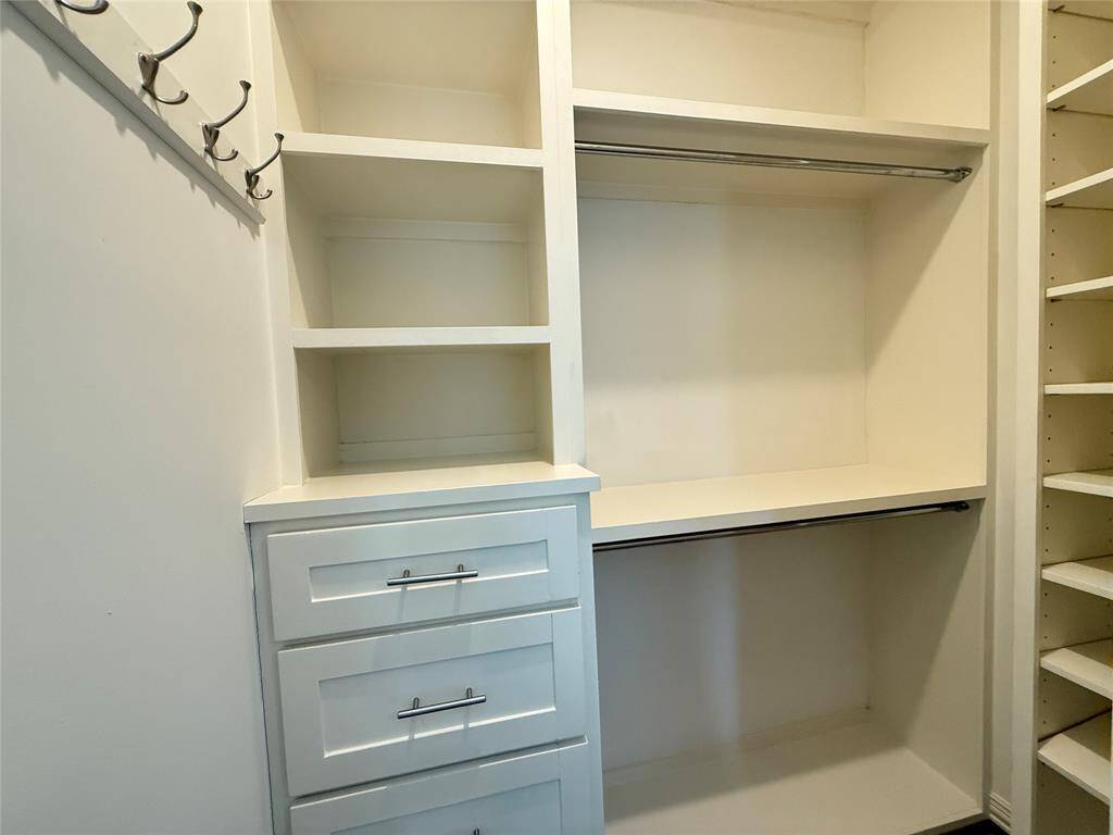 This photo showcases a spacious walk-in closet featuring built-in shelves and drawers, dual hanging rods, and wall hooks for added organization.