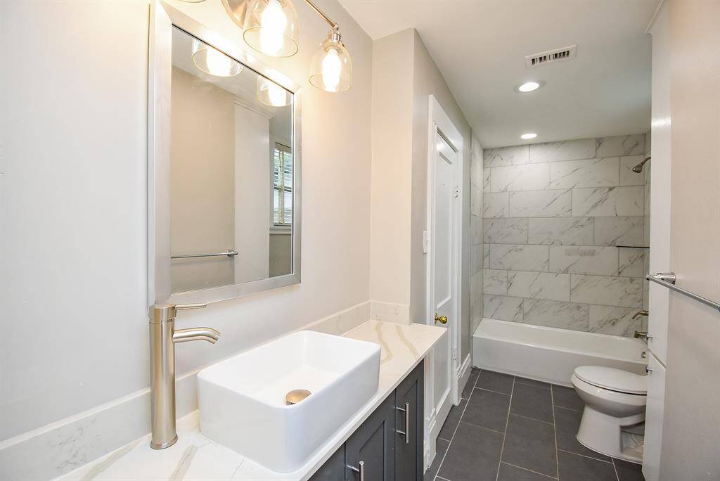 Vanity equipped with a contemporary raised basin sink and elegant lighting.
