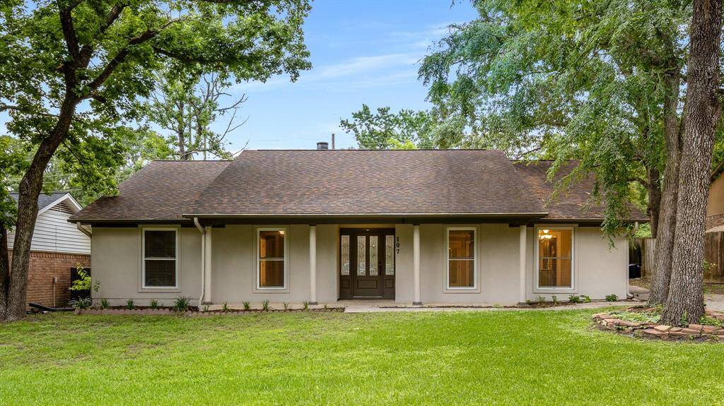 West facing front entrance to ranch style home with mature trees
