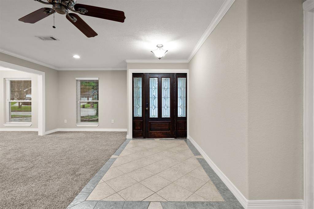 Tiled entryway with rich wood framed glass allows natural light in. Great space for statement console table adorned with fresh florals or a bold mirror.