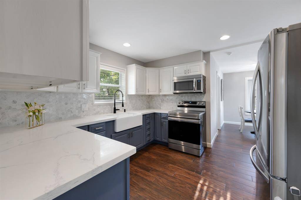 The Kitchen area is also beautifully updated with a new backsplash, open shelves, and a spacious farm sink. Dark blue lower cabinets add a stylish pop of color, complemented by a pantry for extra storage.
