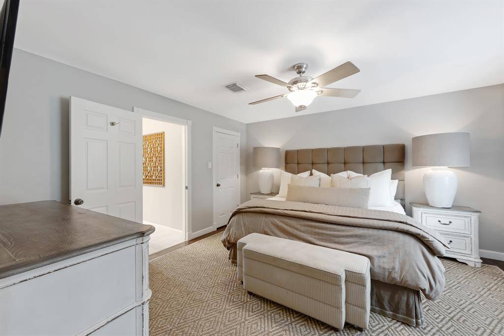 The primary bedroom features a sleek white ceiling fan, hardwood LVP floors and elegant crown molding. A serene retreat with clean lines.