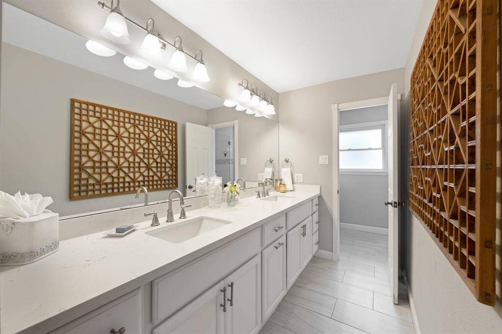 The bathroom features light gray tiled floors that complement the home’s overall palette. White cabinets, a granite countertop with dual sinks. Elegance is found on the little details.