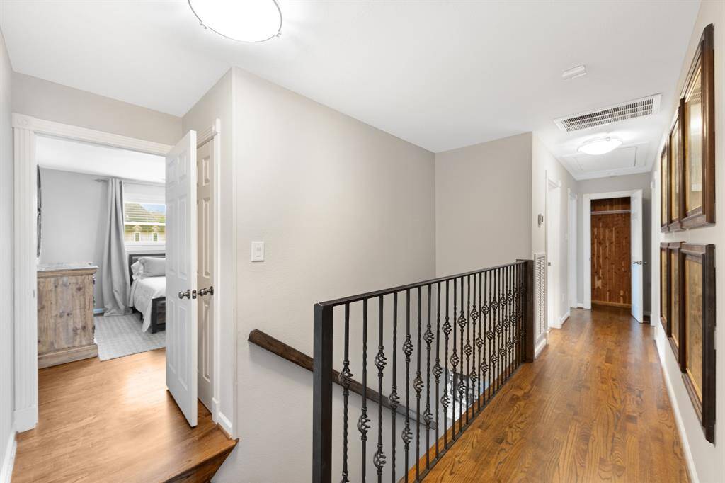 Upstairs hallway features elegant rod iron spindles and hardwood floors, leading to a unique cedar-lined closet—a rare feature for homes in this area, offering natural protection and a fresh scent for stored items.