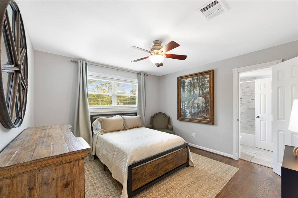 Spacious upstairs bedroom boasts elegant wood tile flooring and a modern ceiling fan. A serene retreat offering comfort and style.
