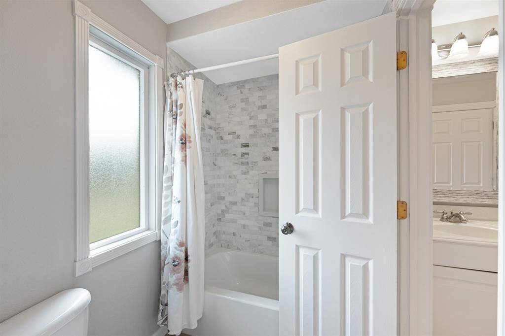 This upstairs guest bathroom offers a sleek shower and tub combo allowing both quick rinses and relaxing soaks.