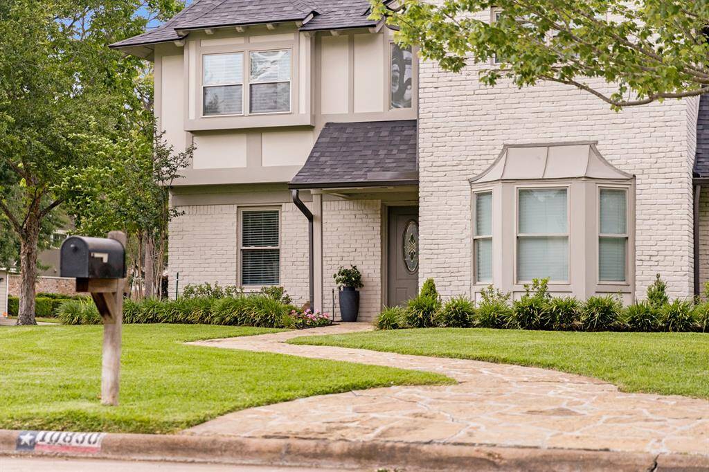 Charming front entrance with a curved stone walkway, manicured landscaping, and a welcoming covered porch.