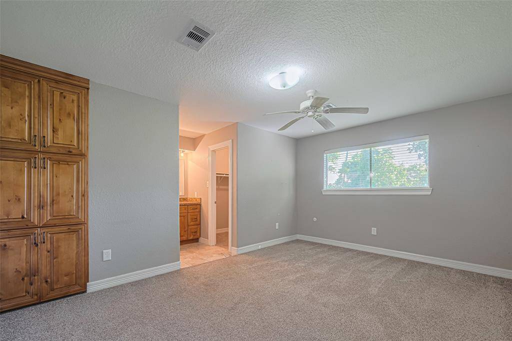 Spacious primary bedroom offers plenty of natural lighting from windows on two walls, a built-in wall storage cabinet, and an en-suite bathroom