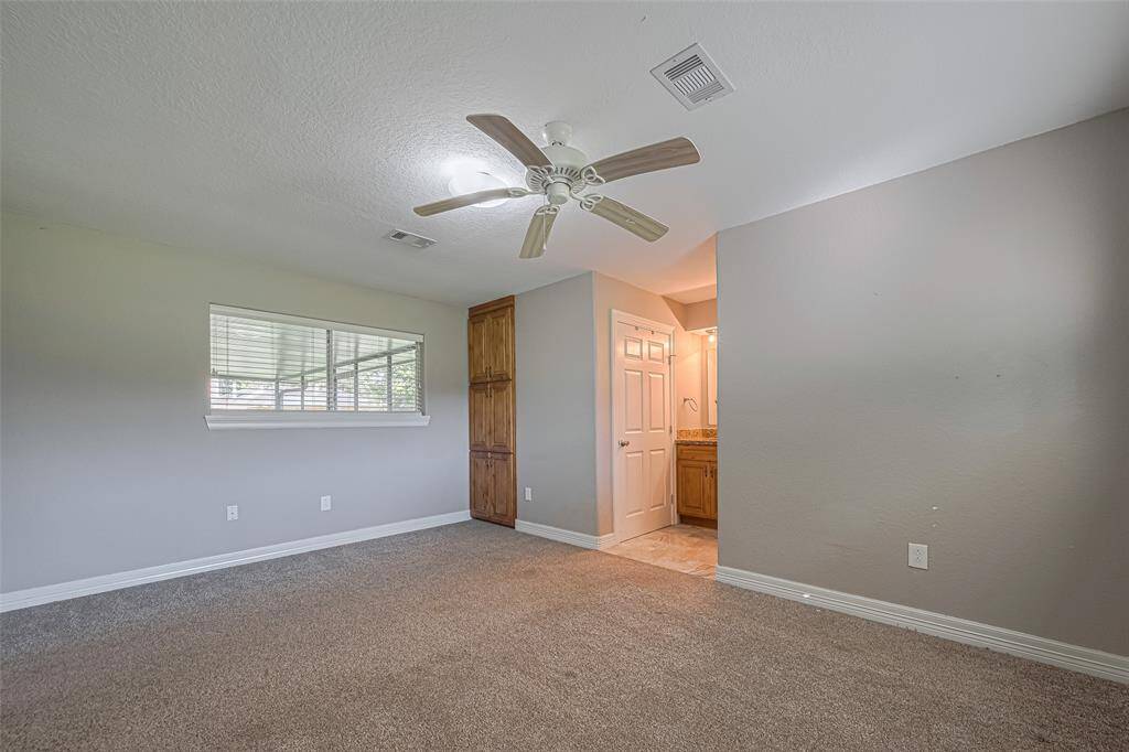 Spacious primary bedroom offers plenty of natural lighting from windows on two walls, a built-in wall storage cabinet, and an en-suite bathroom