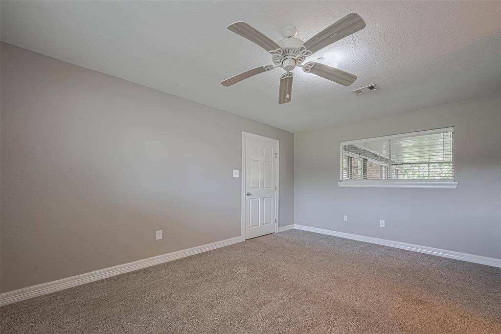 Spacious primary bedroom offers plenty of natural lighting from windows on two walls, a built-in wall storage cabinet, and an en-suite bathroom
