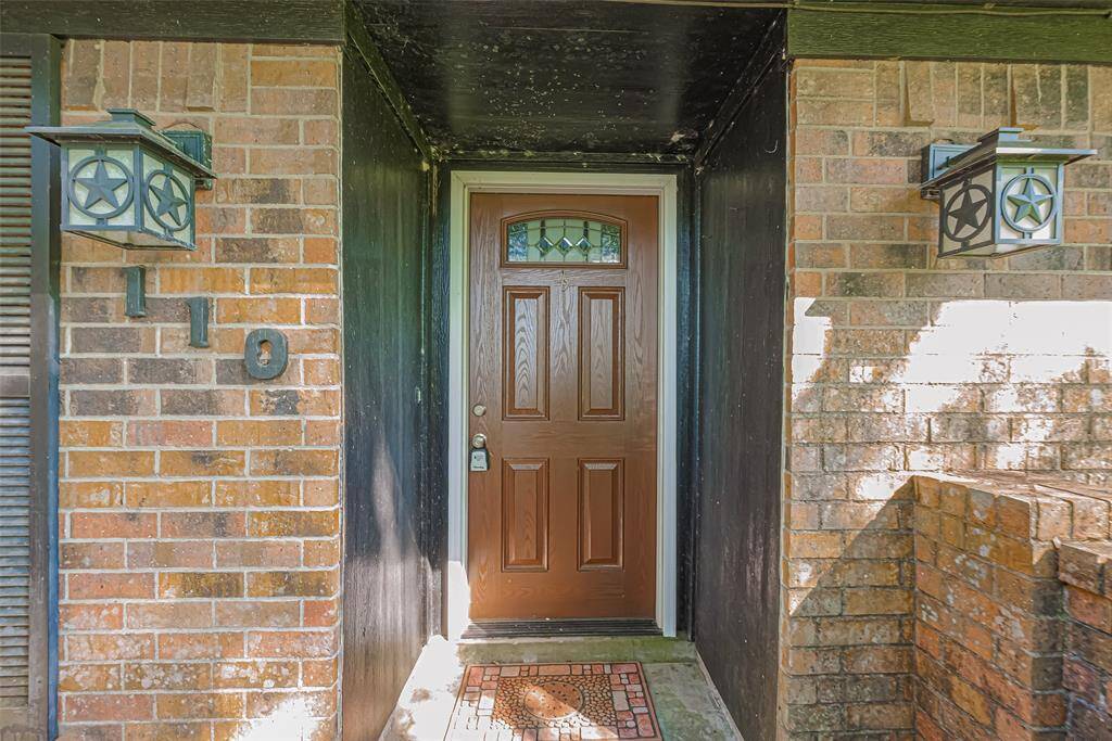 Impressive brick entrance with a wooden front door featuring decorative glass. Flanked by star-themed lanterns, it offers a welcoming and charming entryway.