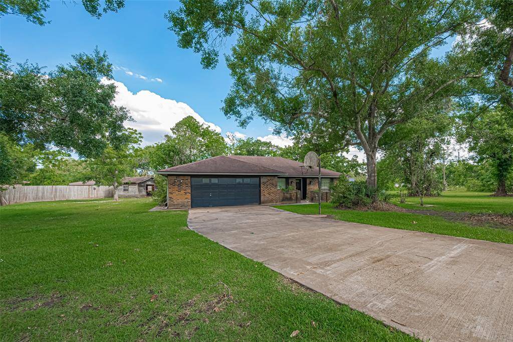 Charming brick home with a two-car garage set amidst lush greenery. The spacious driveway and mature trees enhance the property’s curb appeal, offering a serene and private atmosphere.