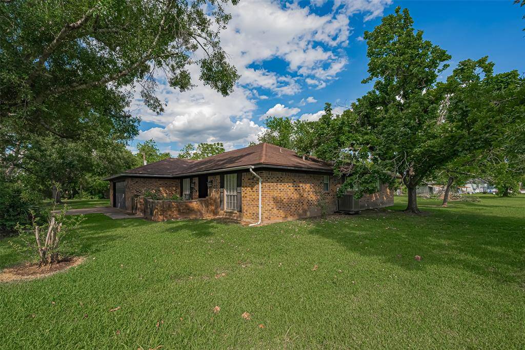 Charming single-story brick home with a spacious front yard and mature trees. Features a wide driveway leading to a two-car garage, offering plenty of parking and outdoor space.