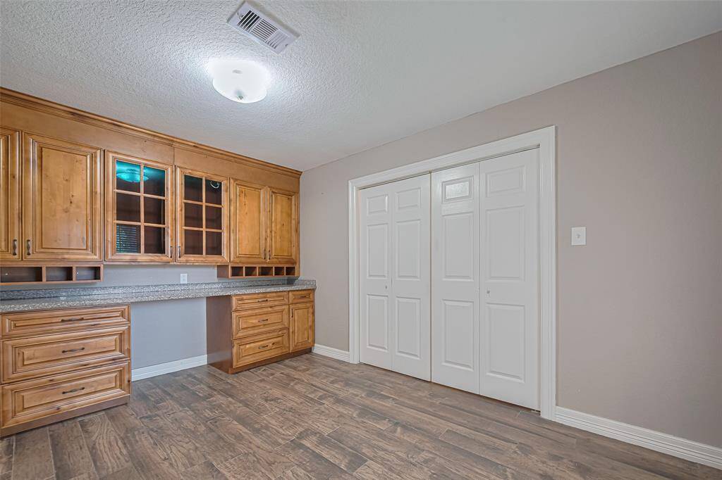 Front room off of entry offers lots of natural lighting, storage, custom built-in wood cabinetry/desk, and double entry privacy doors that makes this perfect for office/study/hobby room