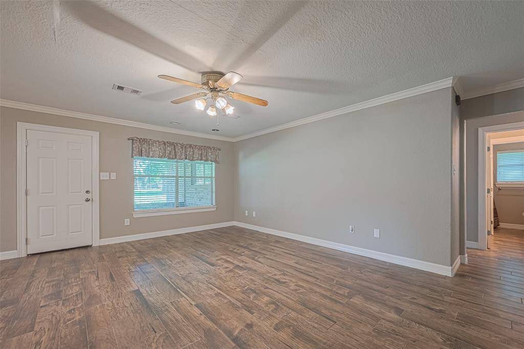 Open concept main living area offers tile flooring, crown molding, and loads of natural lighting from a large picture window overlooking the sunroom and lush backyard