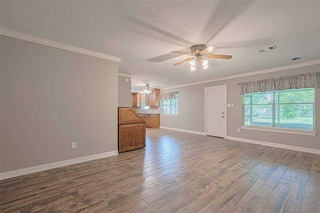 Open concept main living area offers tile flooring, crown molding, and loads of natural lighting from a large picture window overlooking the sun room and lush backyard