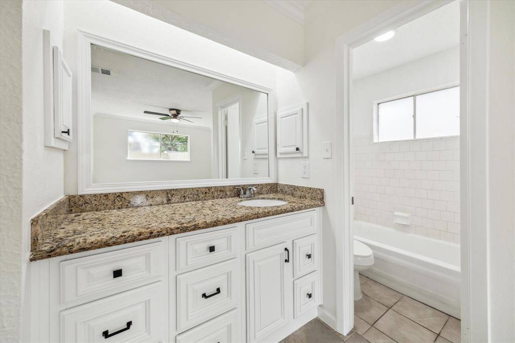 UPDATED PRIMARY BATHROOM WITH GRANITE COUNTERTOP AND AMPLE STORAGE.