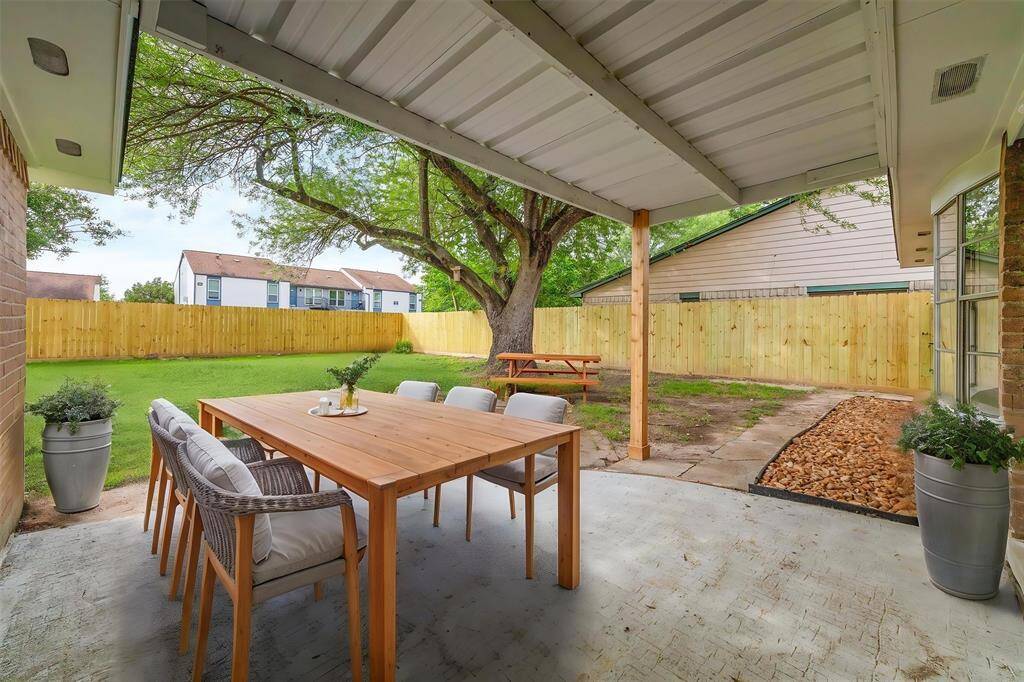 ENJOY SHADED OUTDOOR LIVING UNDER A COVERED PATIO OVERLOOKING THE EXPANSIVE BACKYARD AND NEW PRIVACY FENCE.