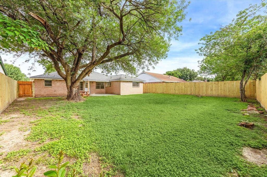 MATURE SHADE TREE AND FRESH PAINTED BRICK CREATE A RELAXED SETTING IN THIS FULLY-FENCED BACKYARD RETREAT.