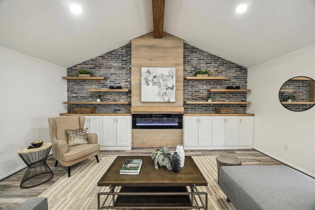 The living room boasts an electric fireplace, a faux brick accent wall with built-in shelving, and additional storage below