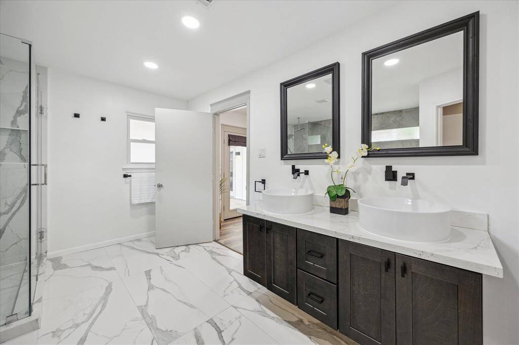 The bathroom boasts quartz countertops, decorative mirrors, and large-scale contemporary tiles for a stylish, modern feel