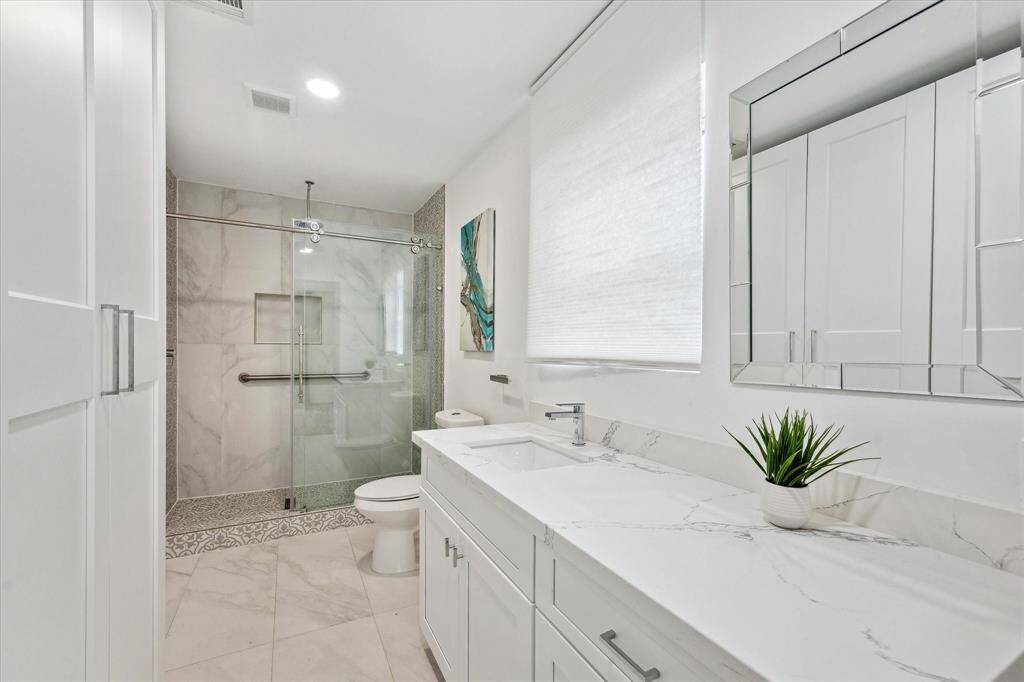 The en-suite bath features quartz countertops, a spacious walk-in shower, and plenty of cabinet storage