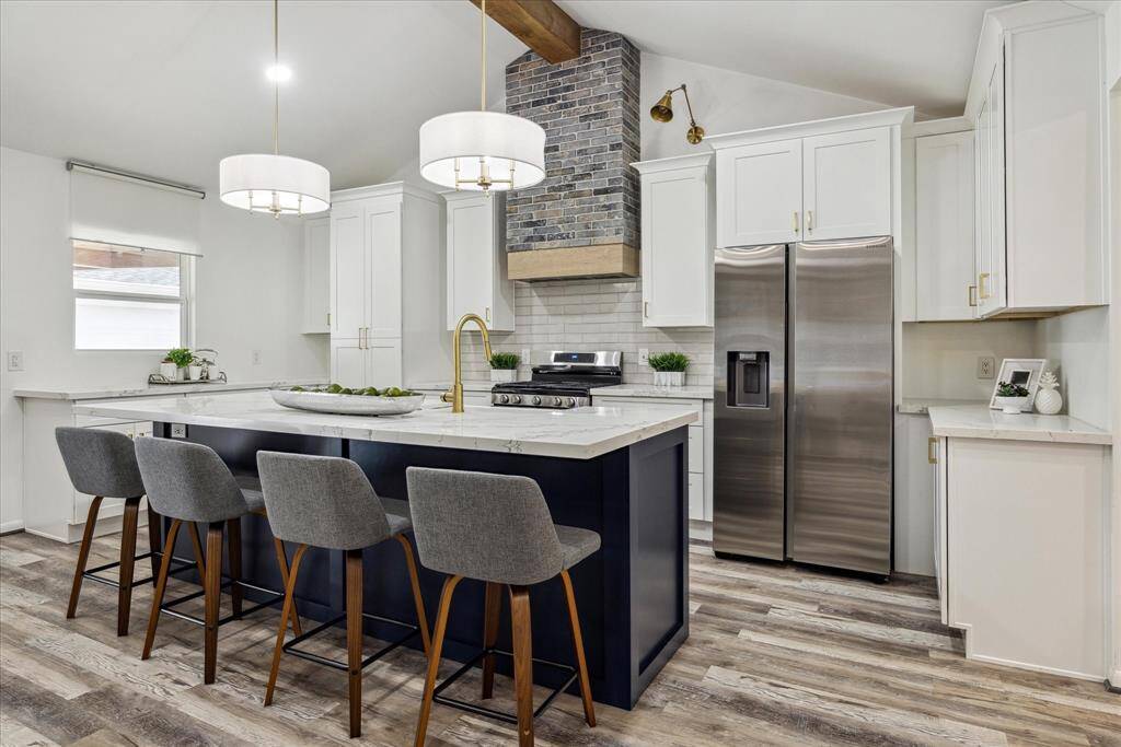 The kitchen is equipped with sleek stainless steel appliances and a statement decorative vent hood