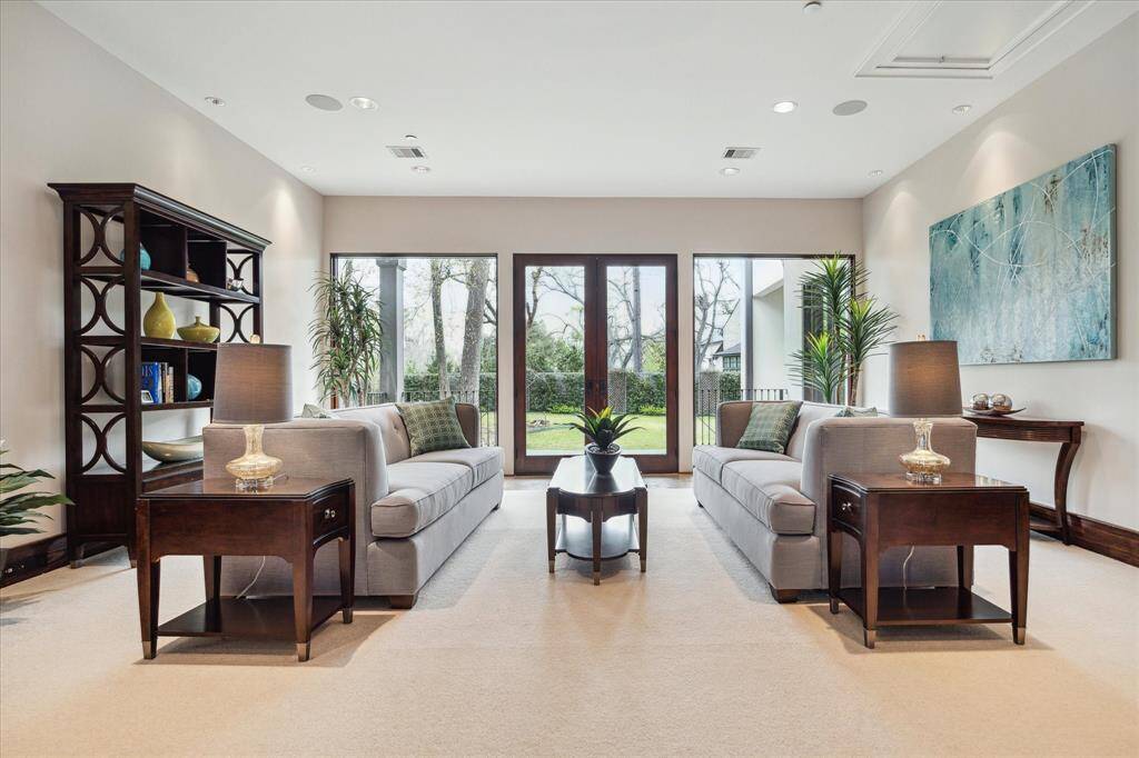 Close up view of the living area/den shows views to the yard and patio with oversized windows and French doors.