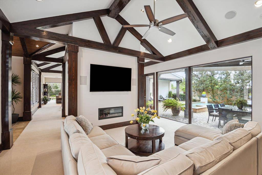 Formal living room to the right of the foyer shows linear glass encased fireplace, floor to ceiling windows, beamed vaulted ceilings... Opens to the huge wet bar, flows to the kitchen and dining room.