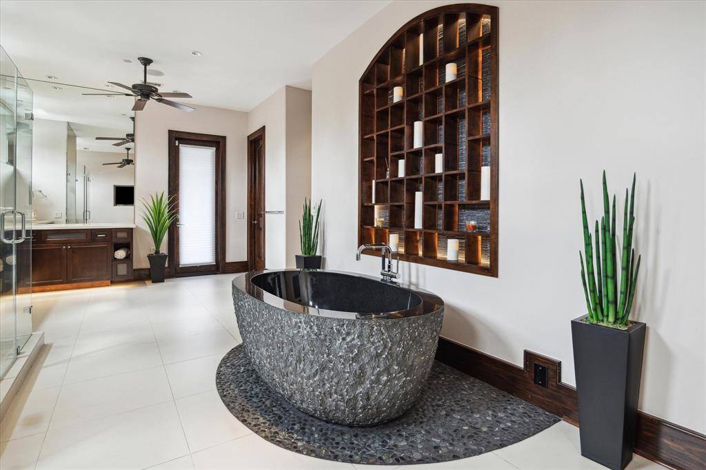 Granite soaking tub with river stone surround accented by a recessed shelving display.