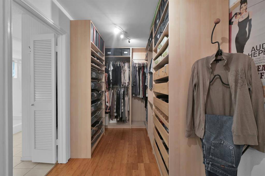 Spacious Custom walk-in dressing area with ample storage, featuring wooden shelving, drawers, and hanging space, perfect for organizing clothing and accessories efficiently.