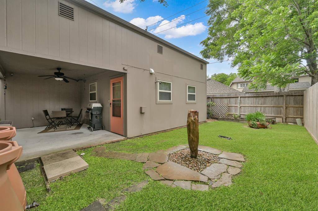 Patio with ceiling fan overlooks the side yard and beautiful water feature.