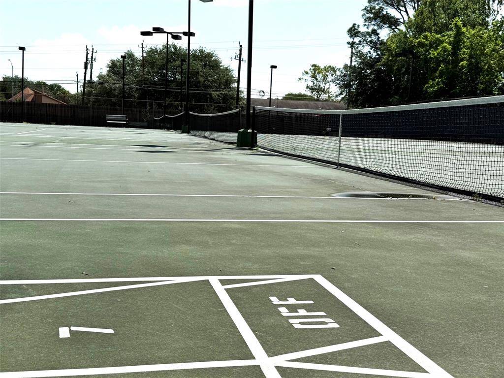 Well-maintained outdoor tennis courts, perfect for sports enthusiasts. It's surrounded by trees and has ample lighting for evening play.
