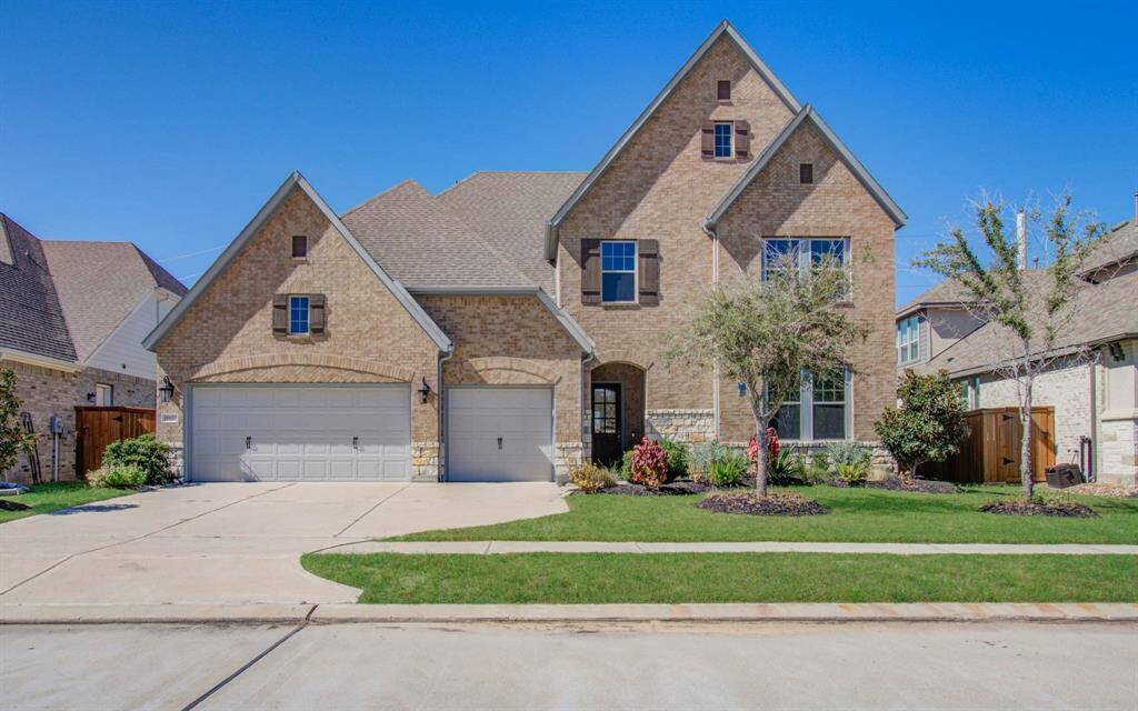 "Stately façade with brick and stone, manicured lawn, and an inviting entrance."