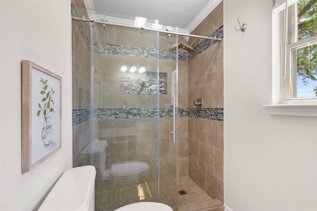Beautiful shower with glass tile inlay and frameless shower sliding door.