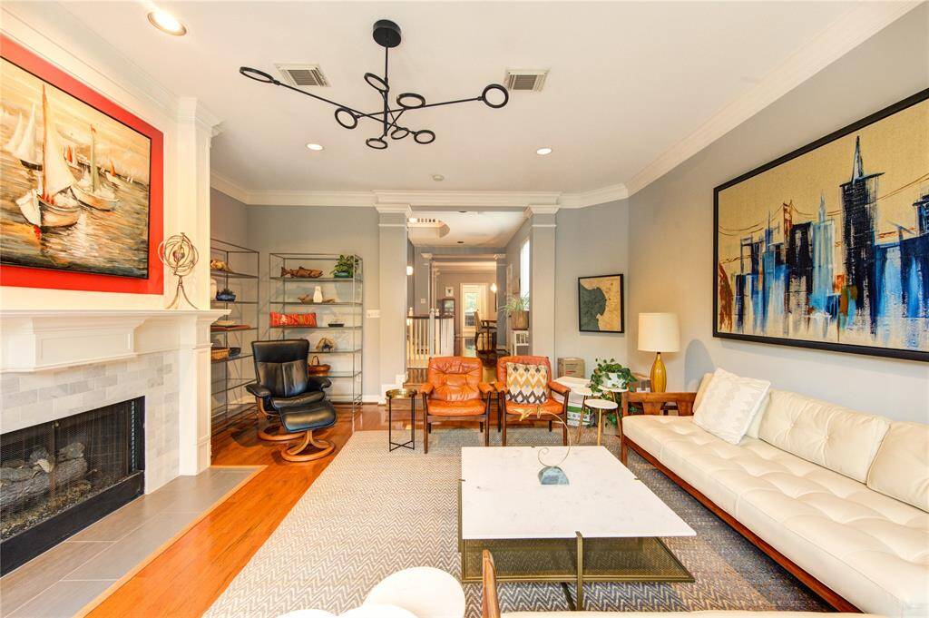 The spacious second-floor living room is the heart of the home, featuring rich hardwood floors that flow seamlessly throughout the open-concept space. A centrally placed fireplace with a modern tile surround creates a stunning focal point, perfect for cozy evenings or stylish entertaining.