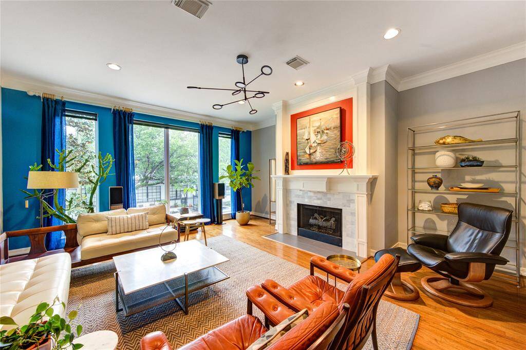 Large windows bathe the room in natural light while offering views of the tree-lined street. High ceilings and recessed lighting enhance the airy, contemporary feel.