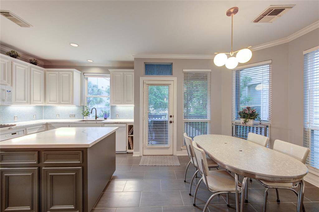 Nestled beside the kitchen, the breakfast nook is surrounded by windows and perfect for casual meals. Overhead modern lighting and a view of the private deck create a serene setting to start your day.