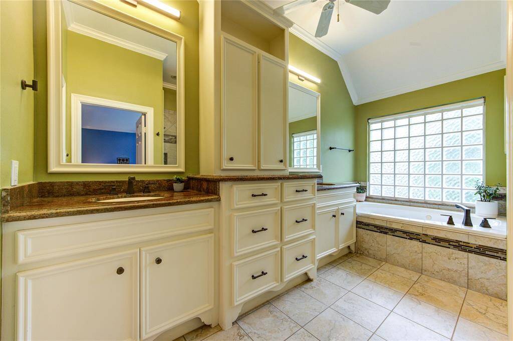 Indulge in the spa-like primary bathroom featuring dual vanities with granite counters, a jetted soaking tub, and a separate walk-in shower with glass enclosure.