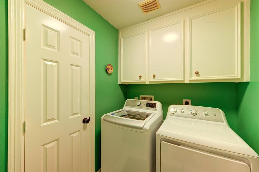 A dedicated laundry room features built-in shelving and full-size washer/dryer connections. Tile flooring provides durability and easy maintenance.