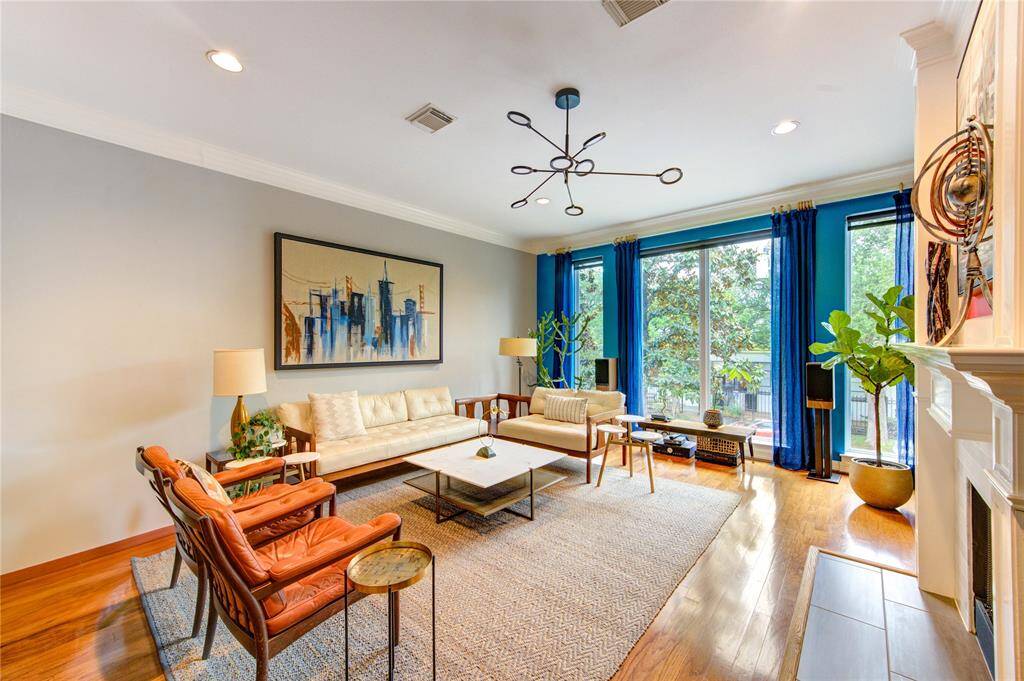 The expansive living area features hardwood flooring, high ceilings, crown molding, and a gas-log fireplace with a traditional mantle—perfect for cozy evenings or elegant entertaining.