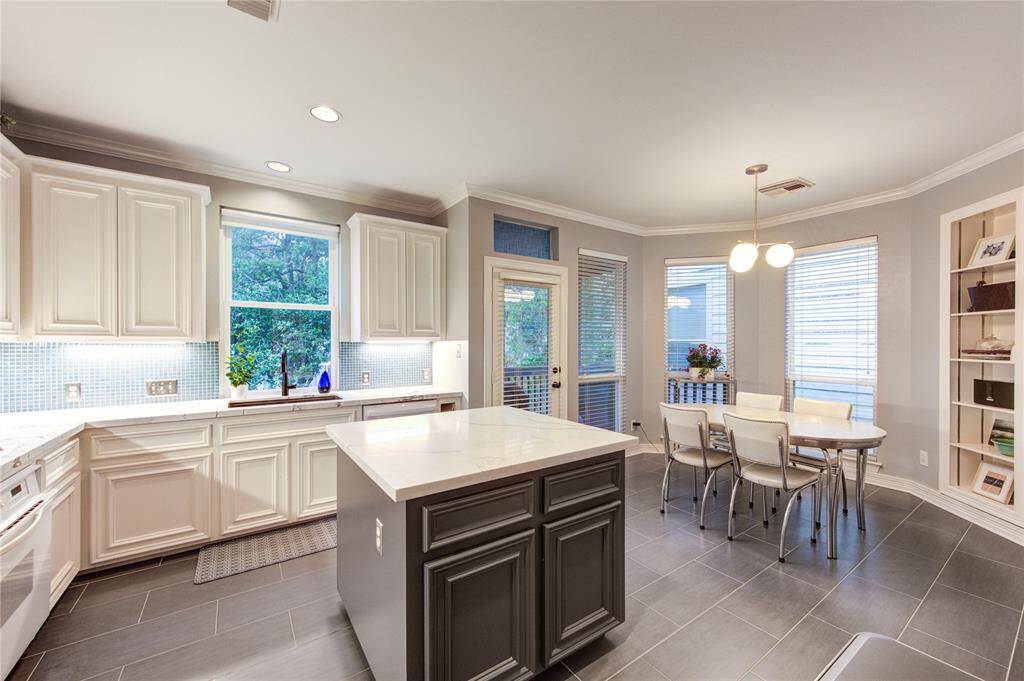 This chef’s kitchen is modernized with Quartz countertops, custom cabinetry, trendy backsplash, and a large center island. This room is filled with natural light and trendy finishes.