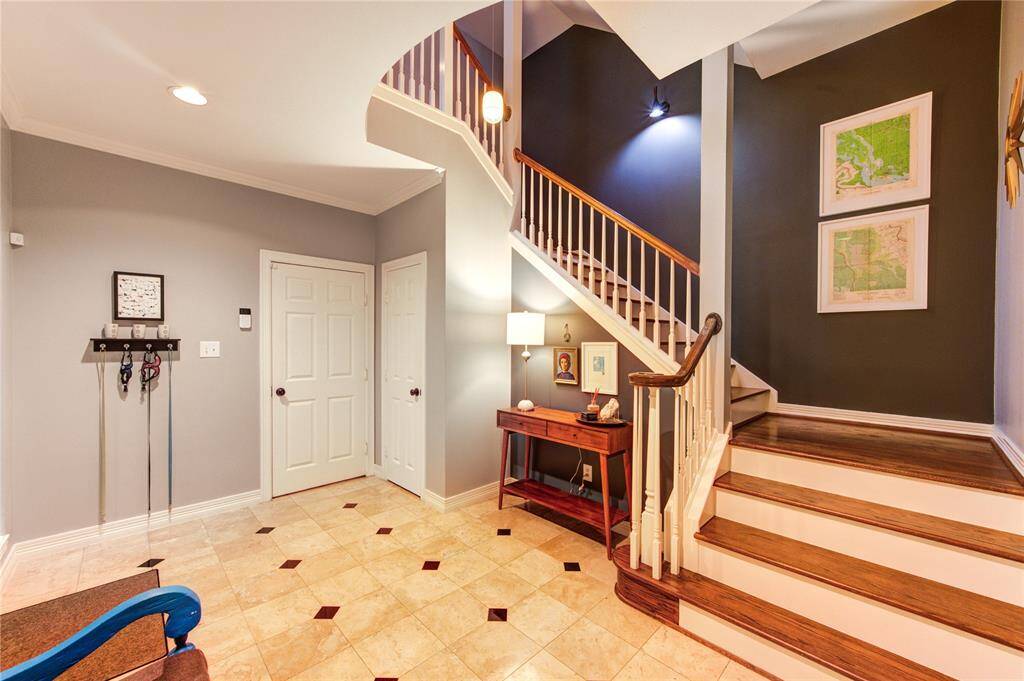 Step inside to soaring ceilings, rich Travertine and hardwood floors, and abundant natural light. The spacious foyer sets the tone for the home’s modern elegance with a sweeping staircase and upgraded lighting fixtures.