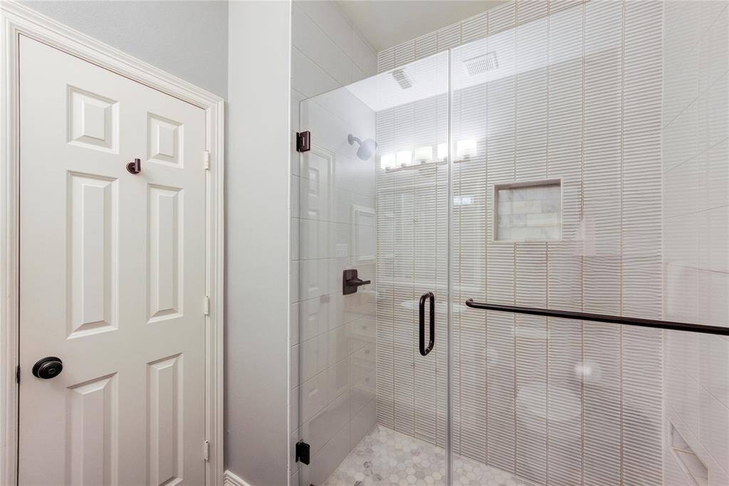 The first-floor bathroom has been thoughtfully modernized to reflect today’s style and functionality. It features a sleek walk-in shower with updated tile surround and a frameless glass door, offering a clean and contemporary look.