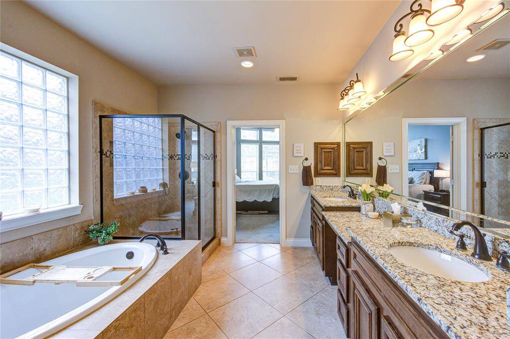 Downstairs primary bathroom offers natural light + separate tub & shower + 2 large primary closets + 2 sinks with a vanity and a private water closet