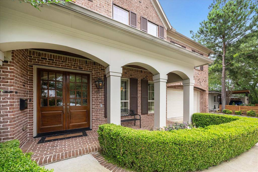 A welcoming covered front porch leads to elegant double doors and a decorative brick entrance, accented by a classic gas lantern for timeless curb appeal.