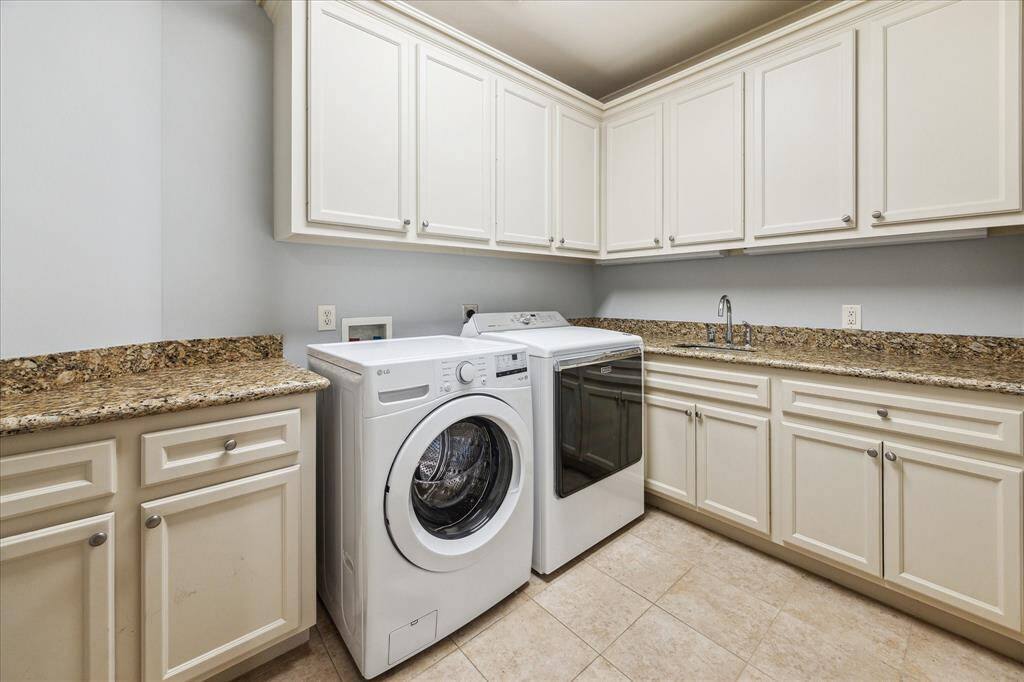 The utility room convenienty features a sink, granite countertops as well as upper and lower cabinets.