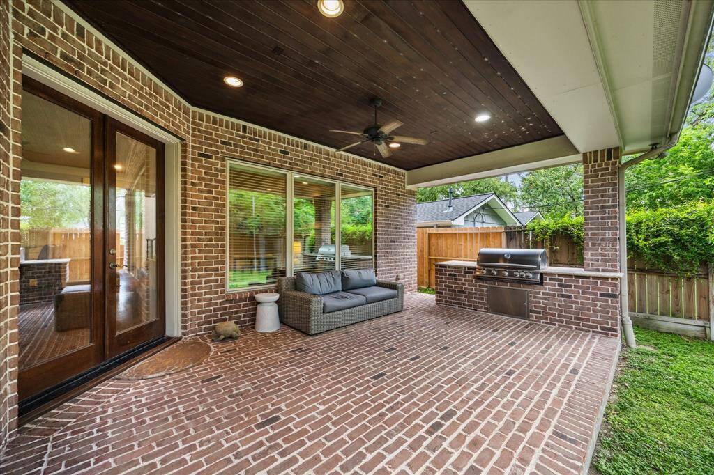 French glass doors open to a covered back patio, complete with an outdoor kitchen and a fenced yard.