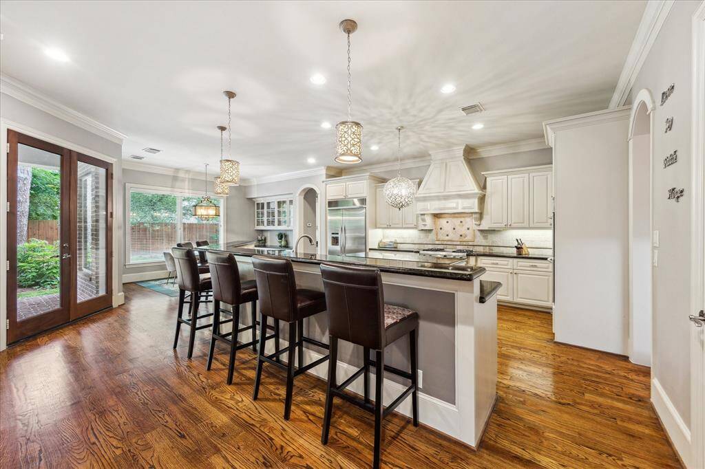 The kitchen is a chef’s delight, featuring a large breakfast bar, granite countertops, stainless steel appliances, and a spacious walk-in pantry.